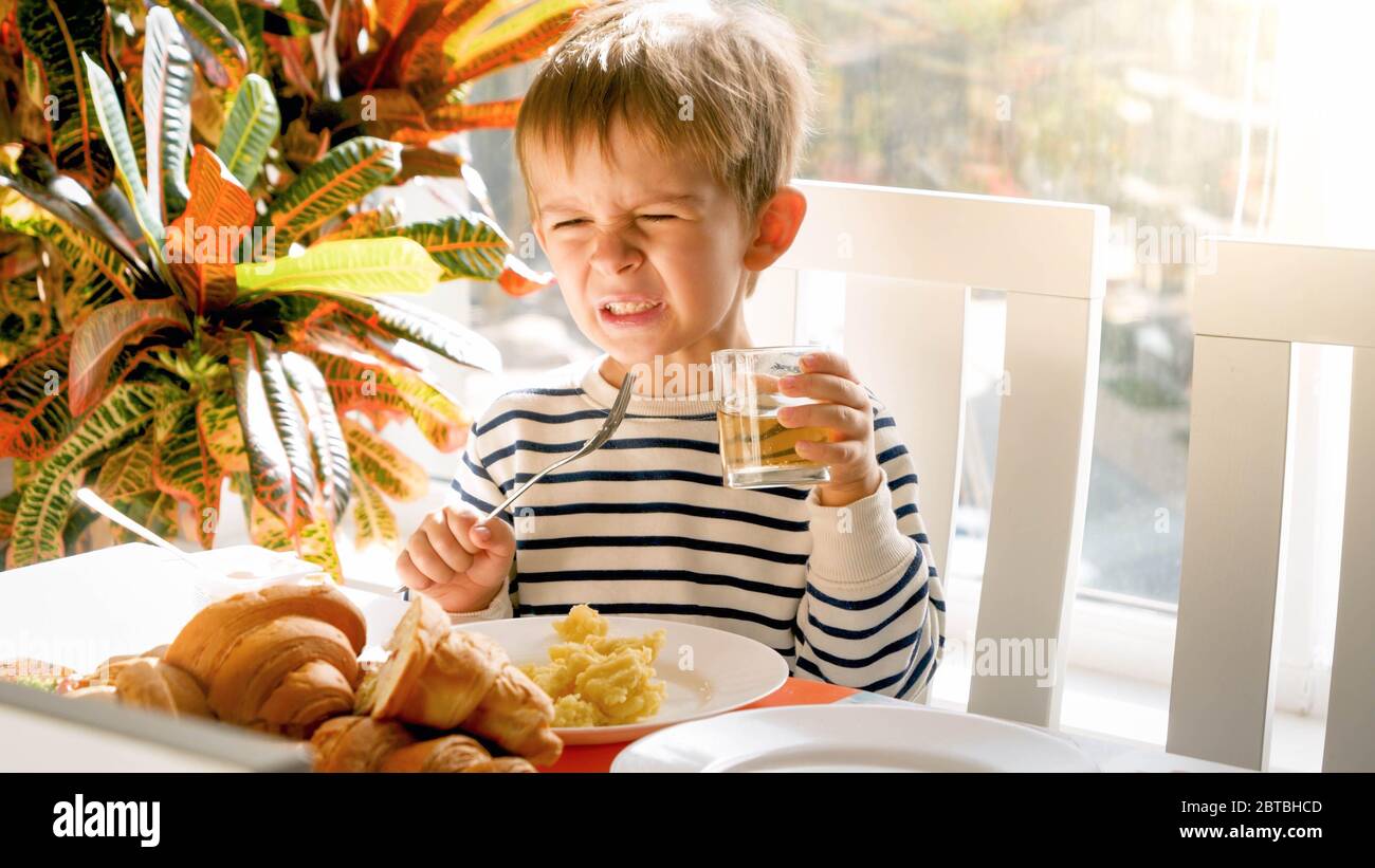 Ritratto del bambino si rifiuta di bere succo durante la colazione nella sala da pranzo Foto Stock