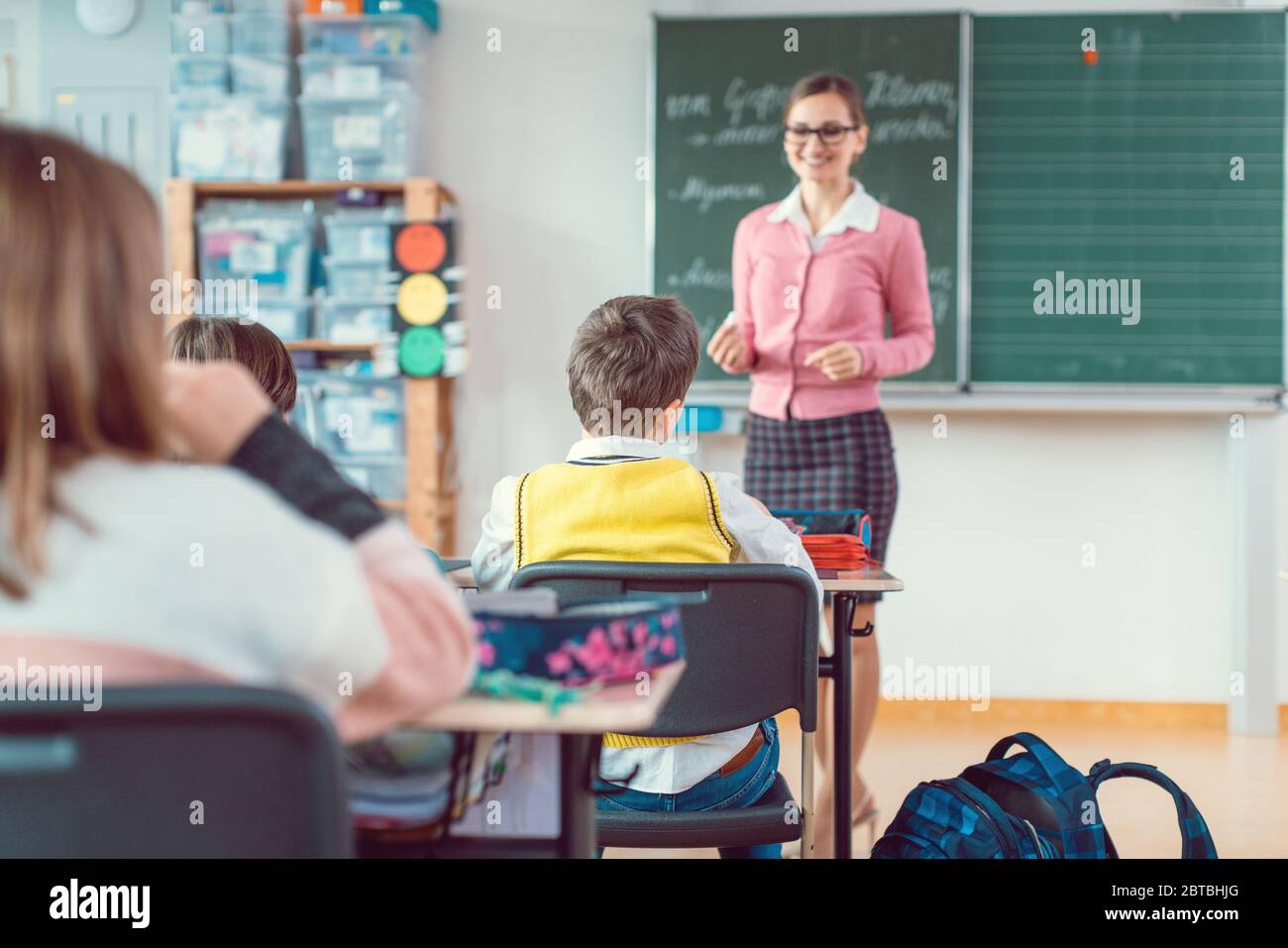 Studenti in classe desiderosi di rispondere a una domanda al loro insegnante Foto Stock