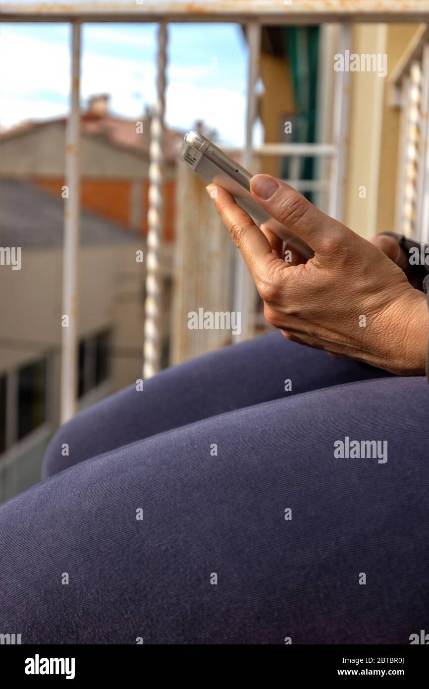 Donna che legge sullo smartphone sul balcone Foto Stock