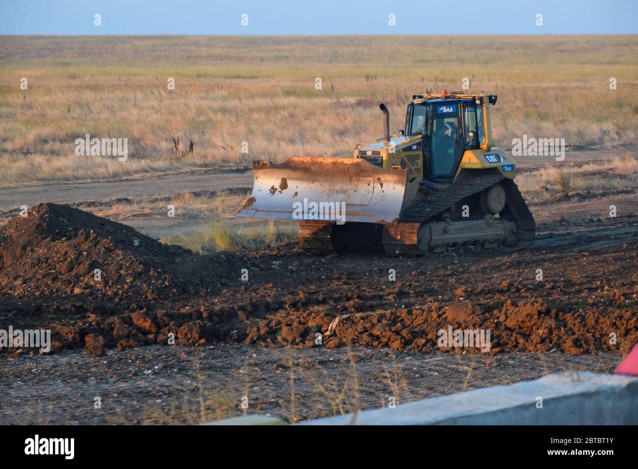 Taman, Russia - 9 luglio 2019: Escavatore sulla costruzione della strada. Macchinari pesanti per l'edilizia. Foto Stock