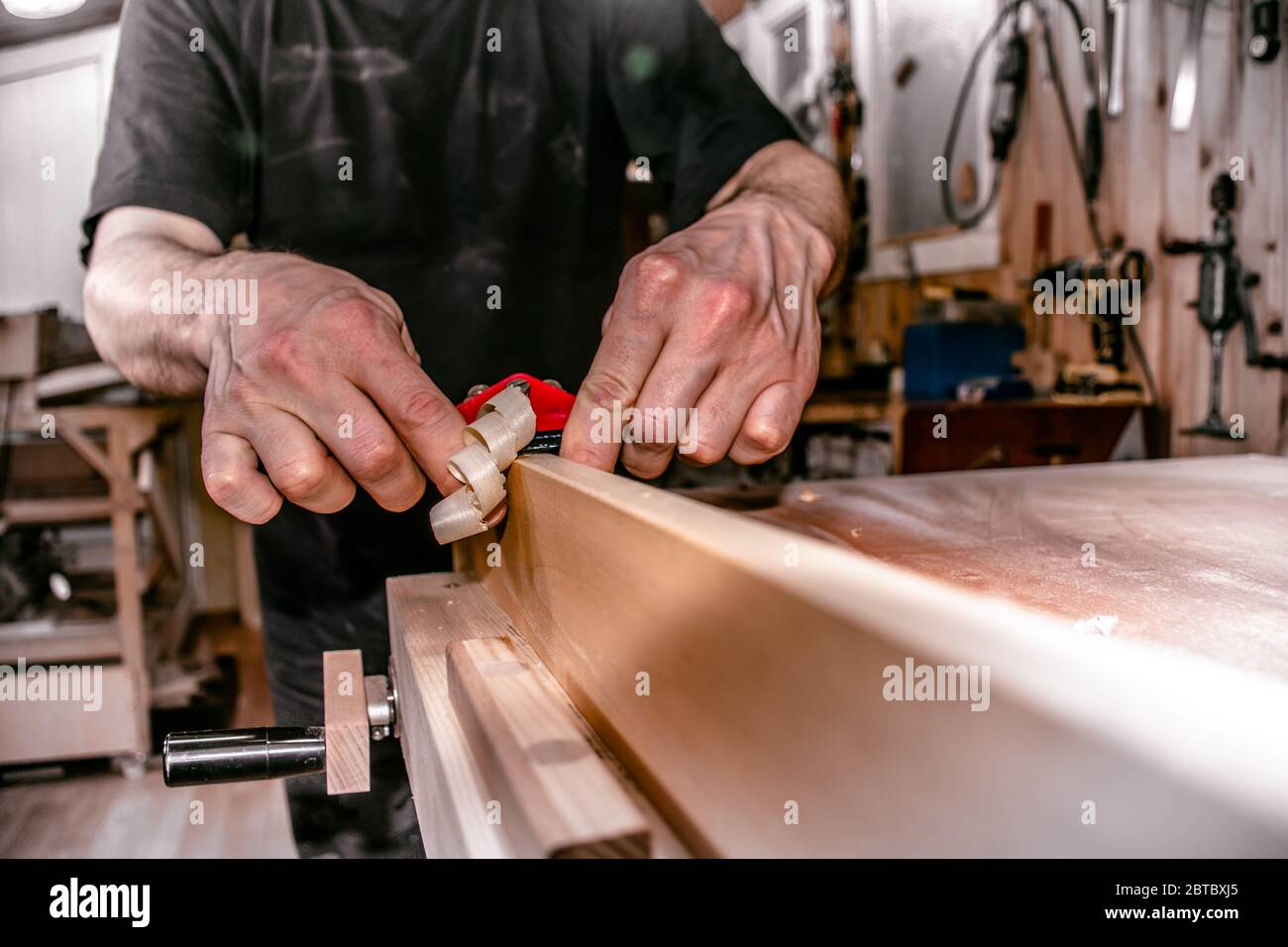 un falegname maschile che lavora in atelier, piallando un pezzo di legno con una doppia mano spingere la piantatrice di uccelli lavorazione legno, primo piano. Foto Stock