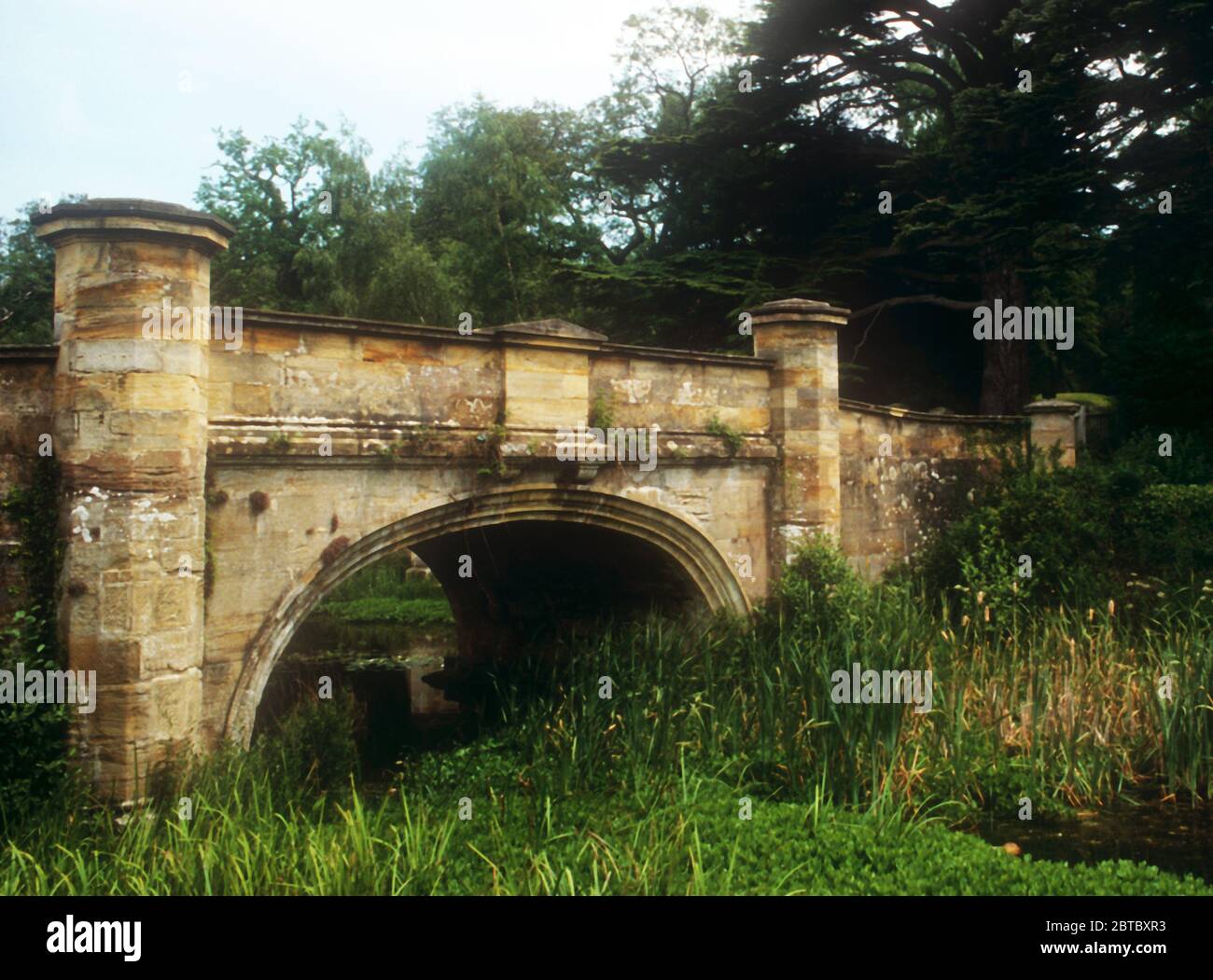 Il ponte in pietra ad arco singolo sull'avvicinamento a Ashburnham Place Foto Stock