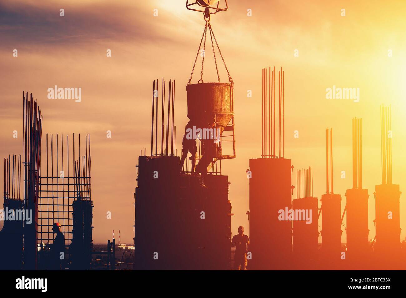 Cantiere con ponteggi e silhouette operaie su sfondo cielo tramonto. Concetto di sviluppo industriale moderno. Foto Stock