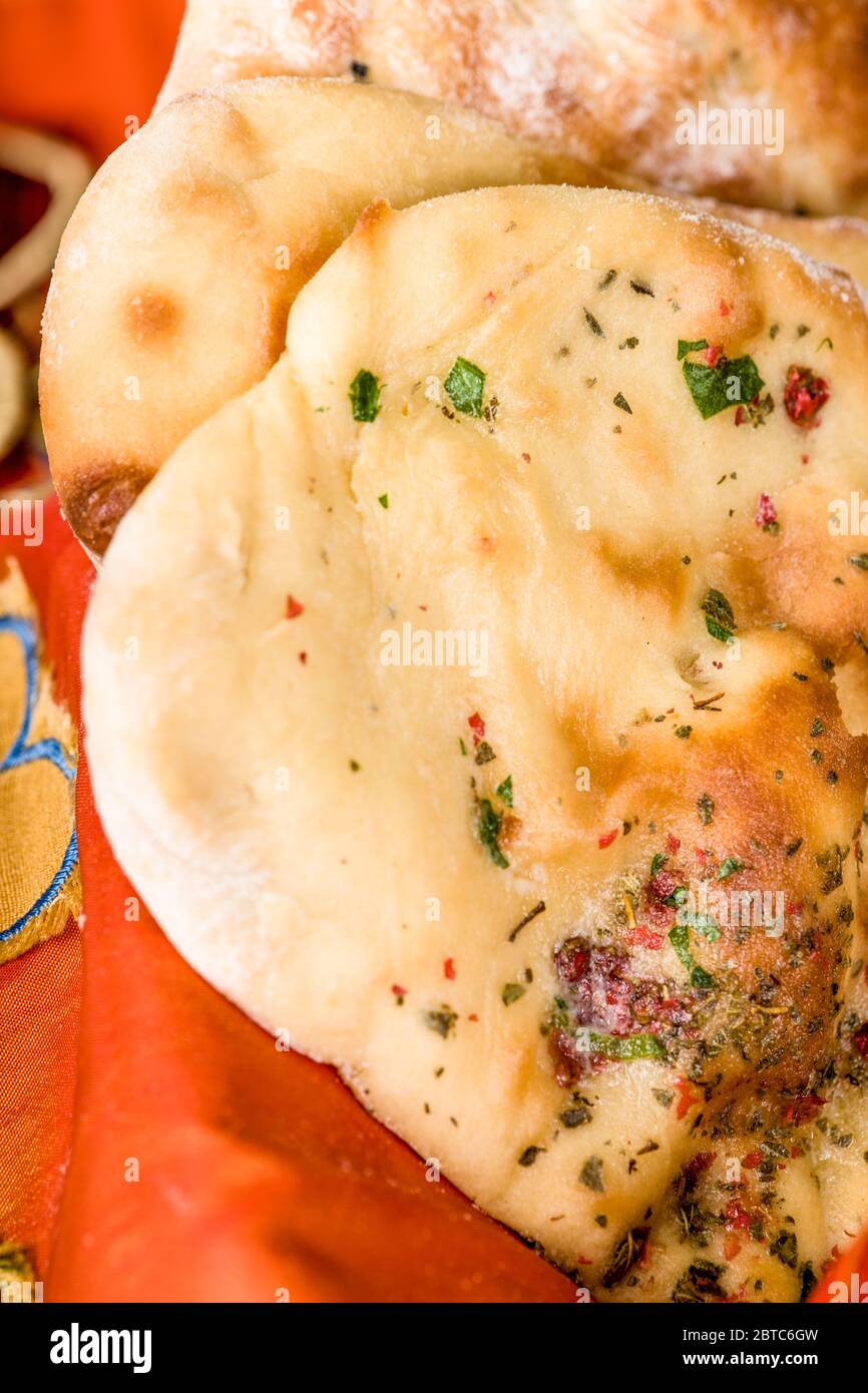 Il modo tradizionale per cuocere il Naan, un pane piatto indiano lievitato, è in un forno di terra o di argilla, ma si può cuocere su una pesante griglia di ferro o padella i Foto Stock