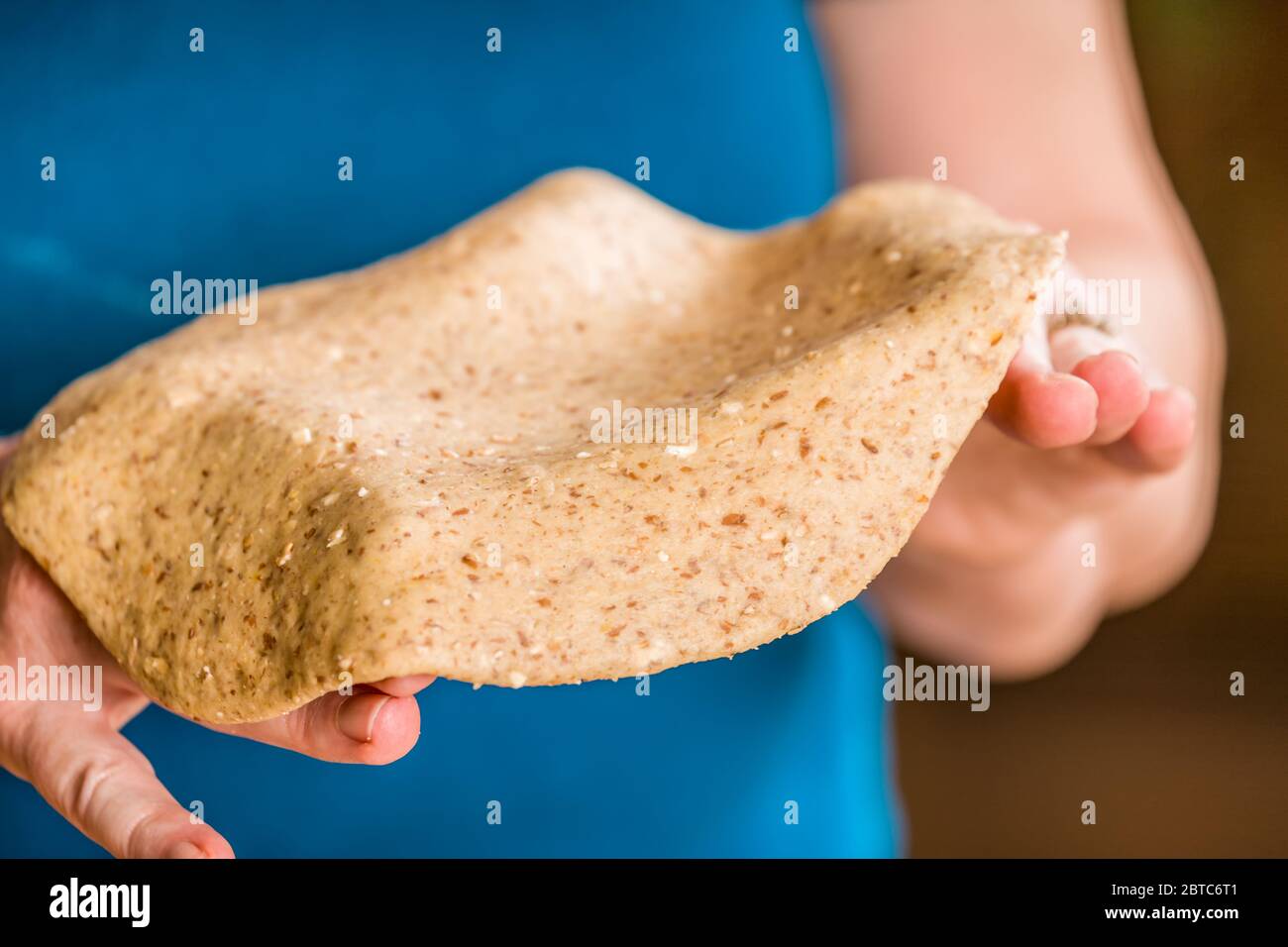 Allungare l'impasto per pizza a grani multipli sulle mani per preparare una pizza a pasta sottile Foto Stock