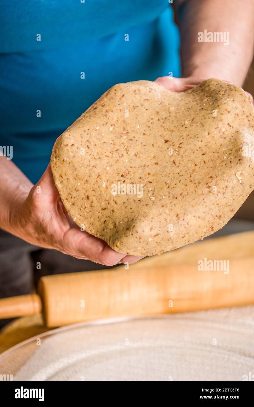 Allungare l'impasto per pizza a grani multipli sulle mani per preparare una pizza a pasta sottile Foto Stock