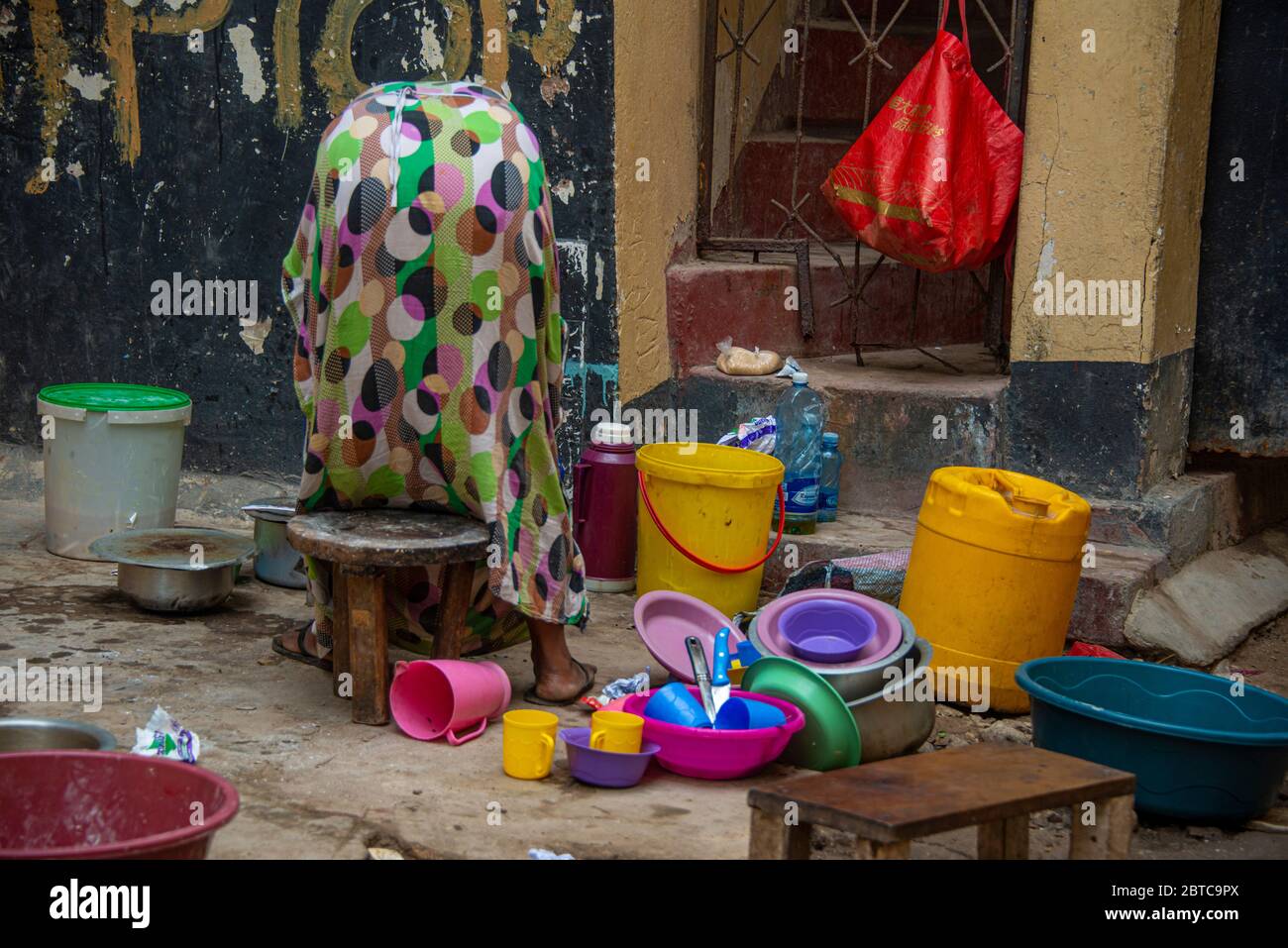 Donna lavaggio piatti per strada a Mombasa Foto Stock