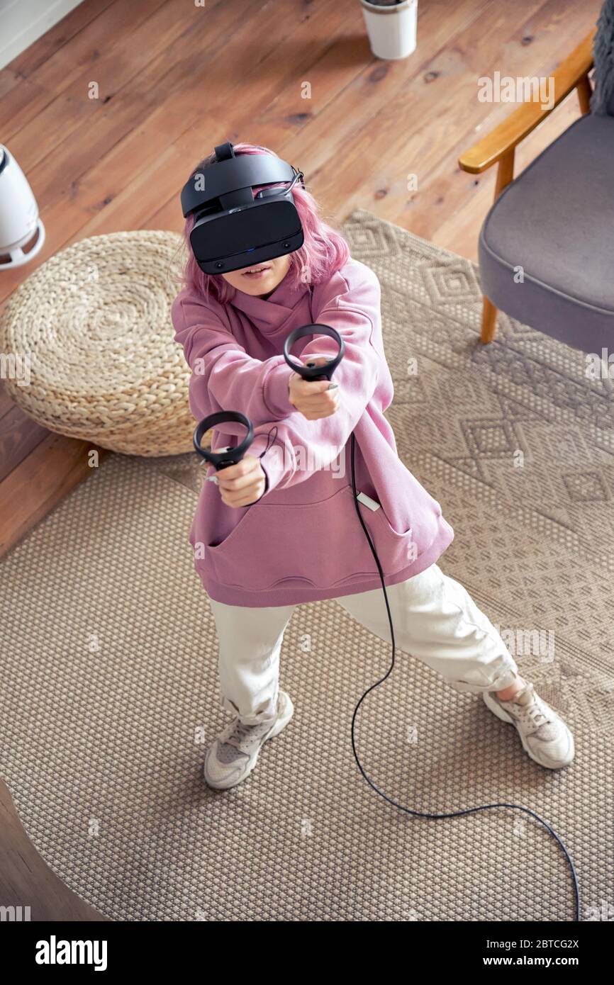 Teen girl wear occhiali vr giocare gioco di realtà virtuale sparare a vista dall'alto della telecamera. Foto Stock