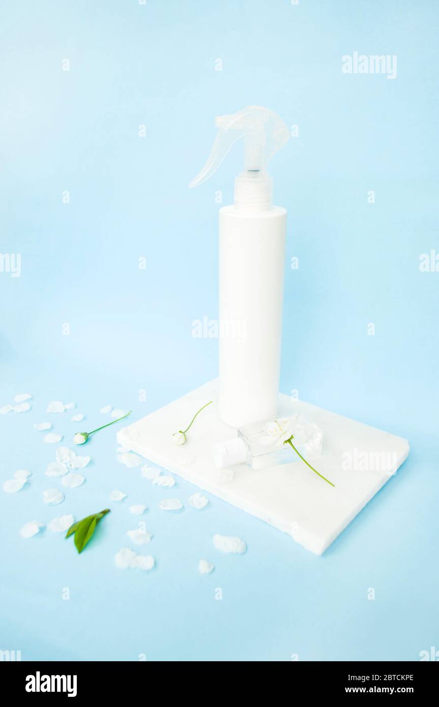 Antisettico a mano in bottiglia spray e beatful fiori fioritura ciliegia albero e foglie verdi fresche su sfondo blu. Stop concetto di coronavirus. Foto Stock