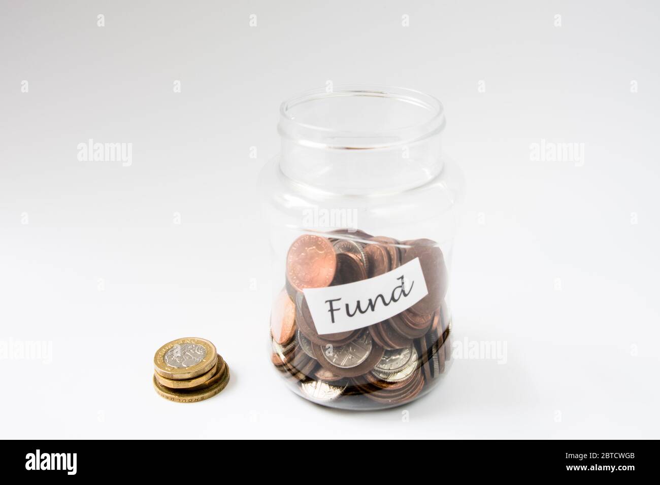 Monete all'interno del vaso etichettato Fund verso il risparmio per un investimento o spese Foto Stock