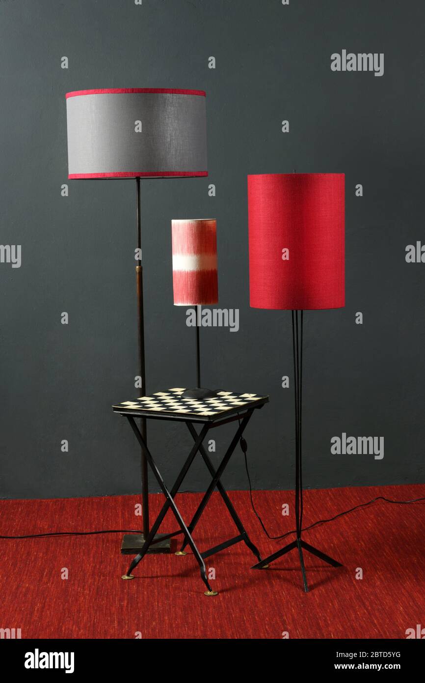Gli interni sono caratterizzati da un'impressionante decorazione rossa e nera con pavimento vintage e lampade da tavolo con sfumature cilindriche contro una parete grigia in un design d'interni Foto Stock