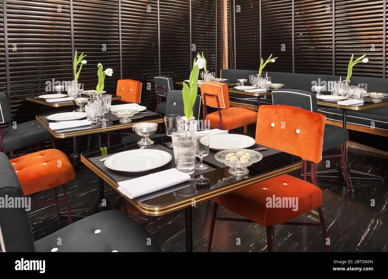 Interni esclusivi del ristorante anni '50 con accenti rossi e decor nero con tavoli da pranzo con centrotavoli floreali Foto Stock