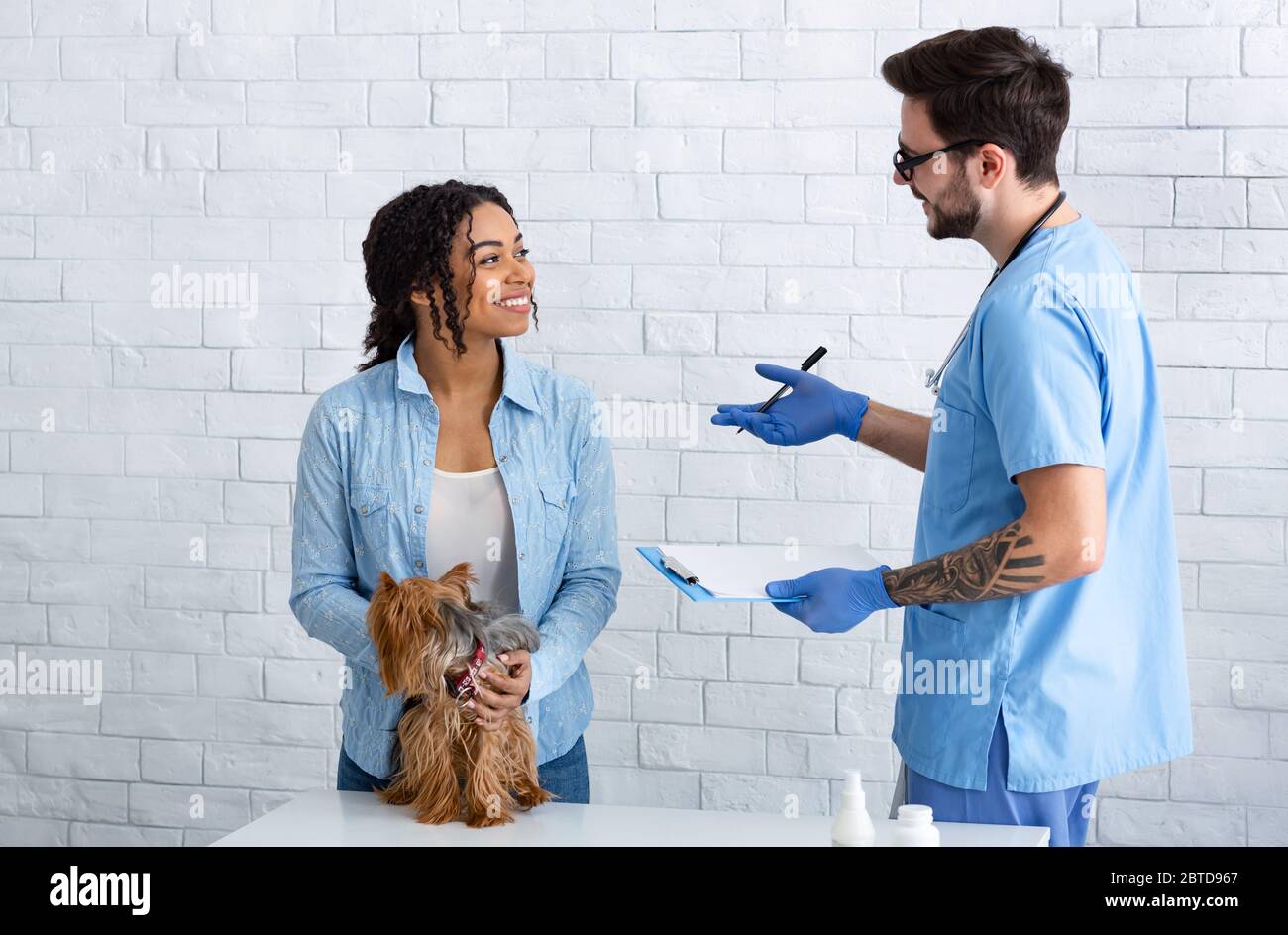 Donna afroamericana con animale domestico in visita al medico veterinario presso la clinica animale Foto Stock