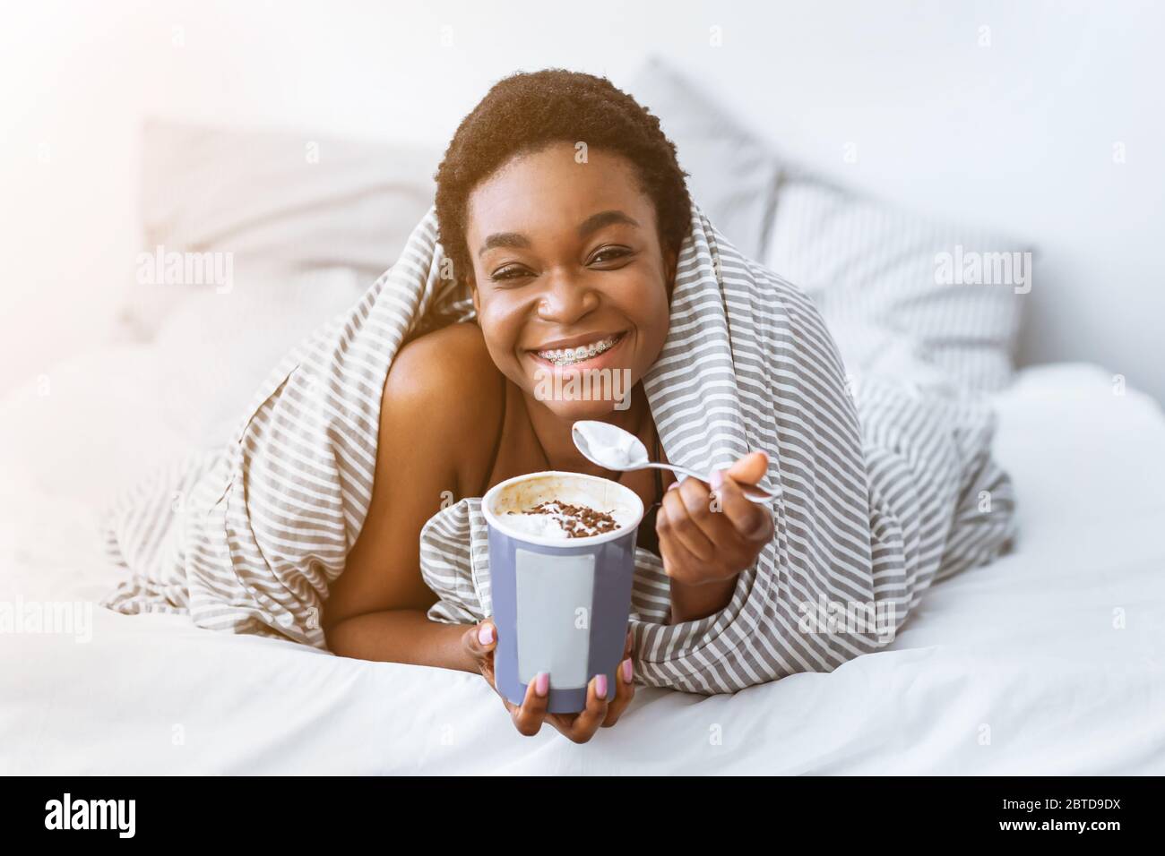 Dente dolce. Ragazza afroamericana con secchio gelato e cucchiaio Foto Stock