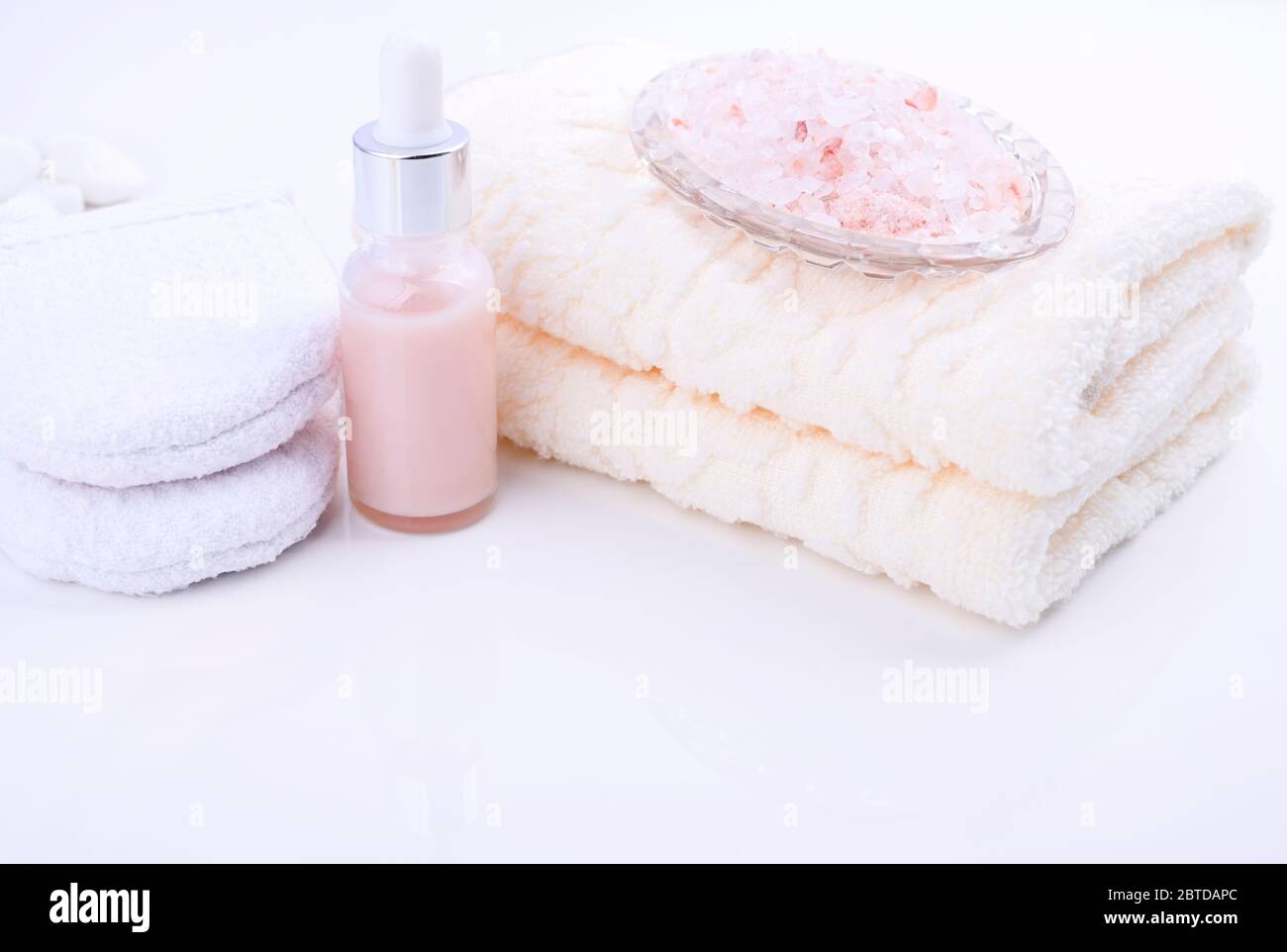 Spa relax e concetto di bagno, sale marino, sapone, con cosmetici e asciugamani su sfondo bianco. Un morbido panno di cotone, sale marino e una spugna per il lavaggio. Messa a fuoco morbida spazio libero per il testo Foto Stock