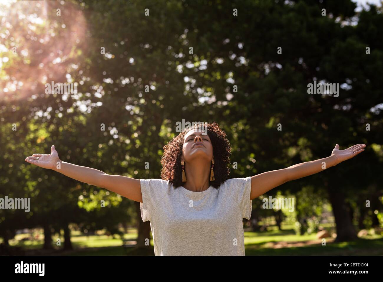 Donna in piedi in un parco con le braccia sollevate verso l'alto Foto Stock