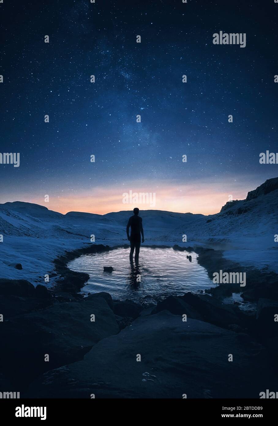 Il viaggiatore si trova in una sorgente calda segreta di notte in Islanda sotto il cielo stellato mozzafiato con la Via Lattea Foto Stock