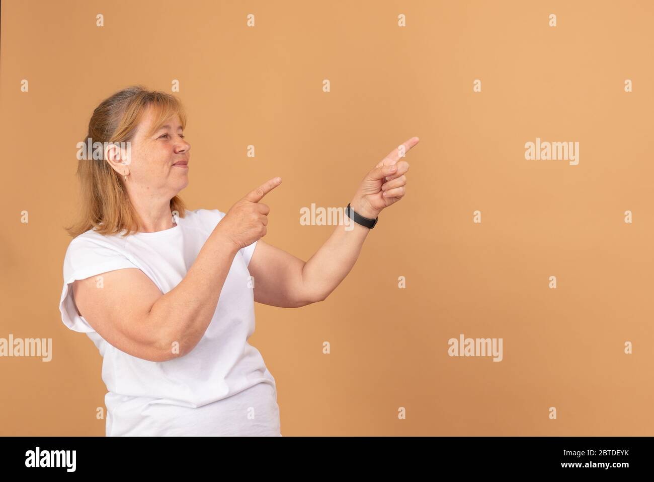 Felice vecchia donna che mostra al copyspace spazio vuoto. Sorridente anziana femmina che tiene le dita puntano a sinistra per vuoto il posto per il testo Foto Stock