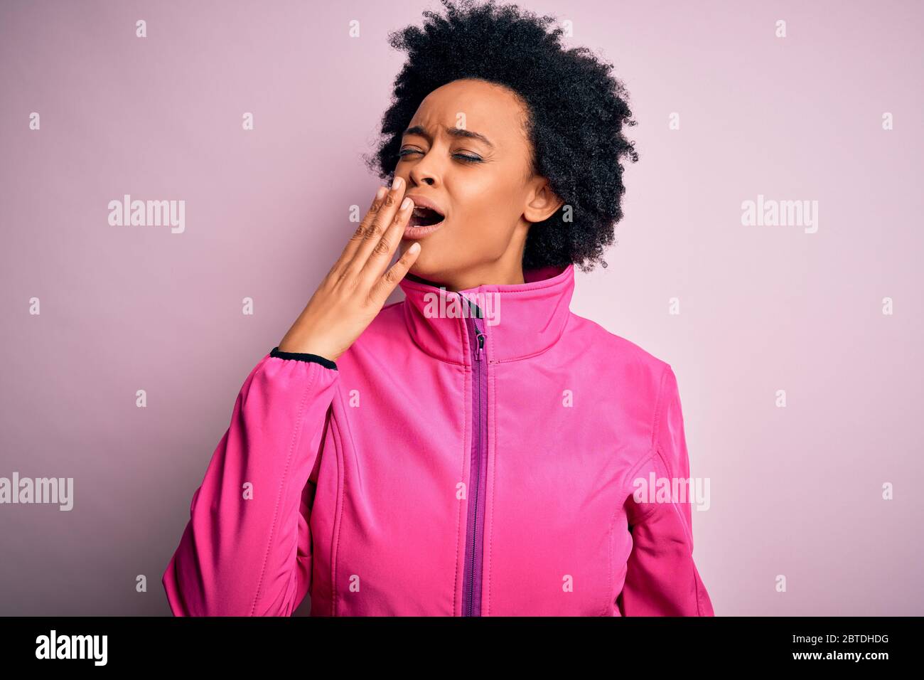 Giovane afroamericano sportivo con capelli ricci che indossa sportswear doin sport annoiato tendente stanco coprendo bocca con mano. Inquietante e sonno Foto Stock
