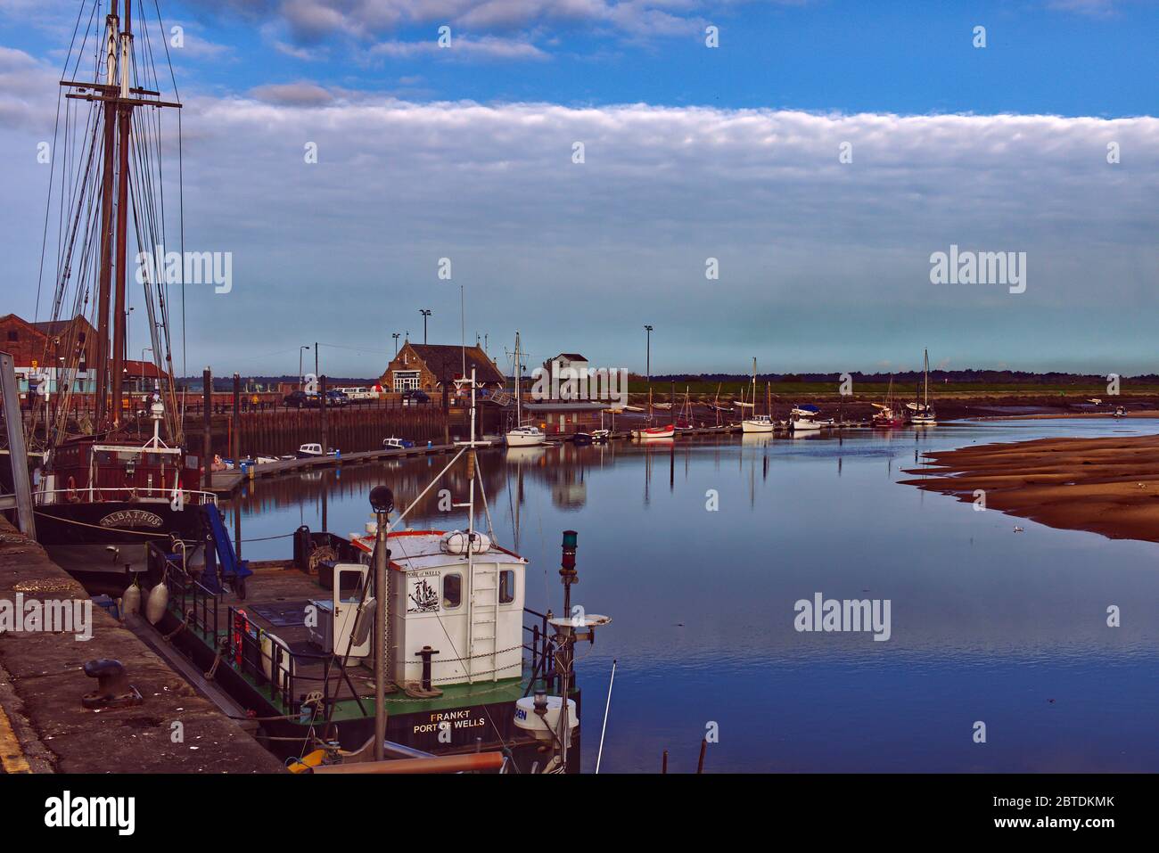 Barche ormeggiate lungo il Quay e l'estuario a bassa marea, Wells-next-the-Sea, Norfolk, Regno Unito Foto Stock