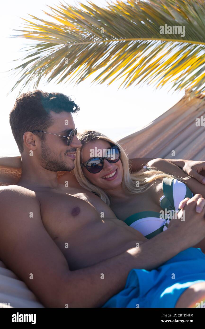 Coppia caucasica adagiata su un'amaca sulla spiaggia. Foto Stock