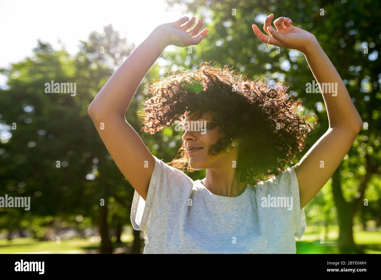 Donna spensierata che danzano in un parco in un pomeriggio soleggiato Foto Stock