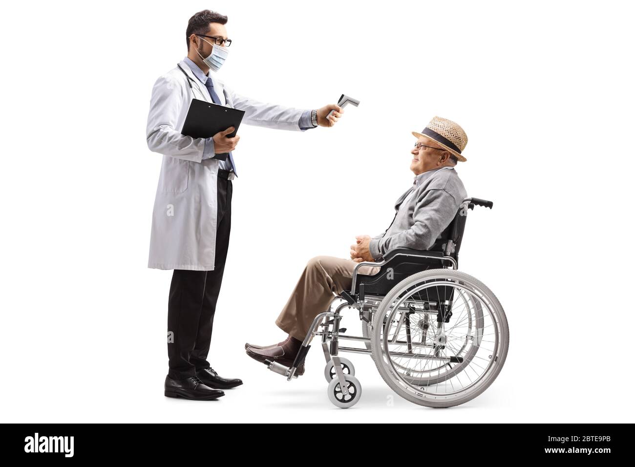 Foto di profilo a lunghezza intera di un medico maschile con un termometro che misura la temperatura di un uomo anziano in una sedia a rotelle isolata su sfondo bianco Foto Stock