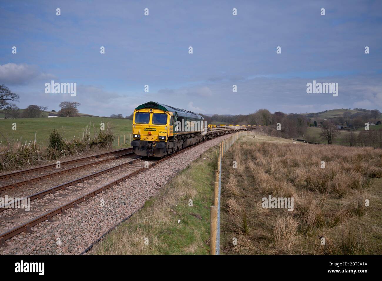 Freightliner classe 66 locomotiva 66596 passando Borwick sulla panoramica linea ferroviaria rurale poco nord-ovest con un treno di ingegneri Foto Stock