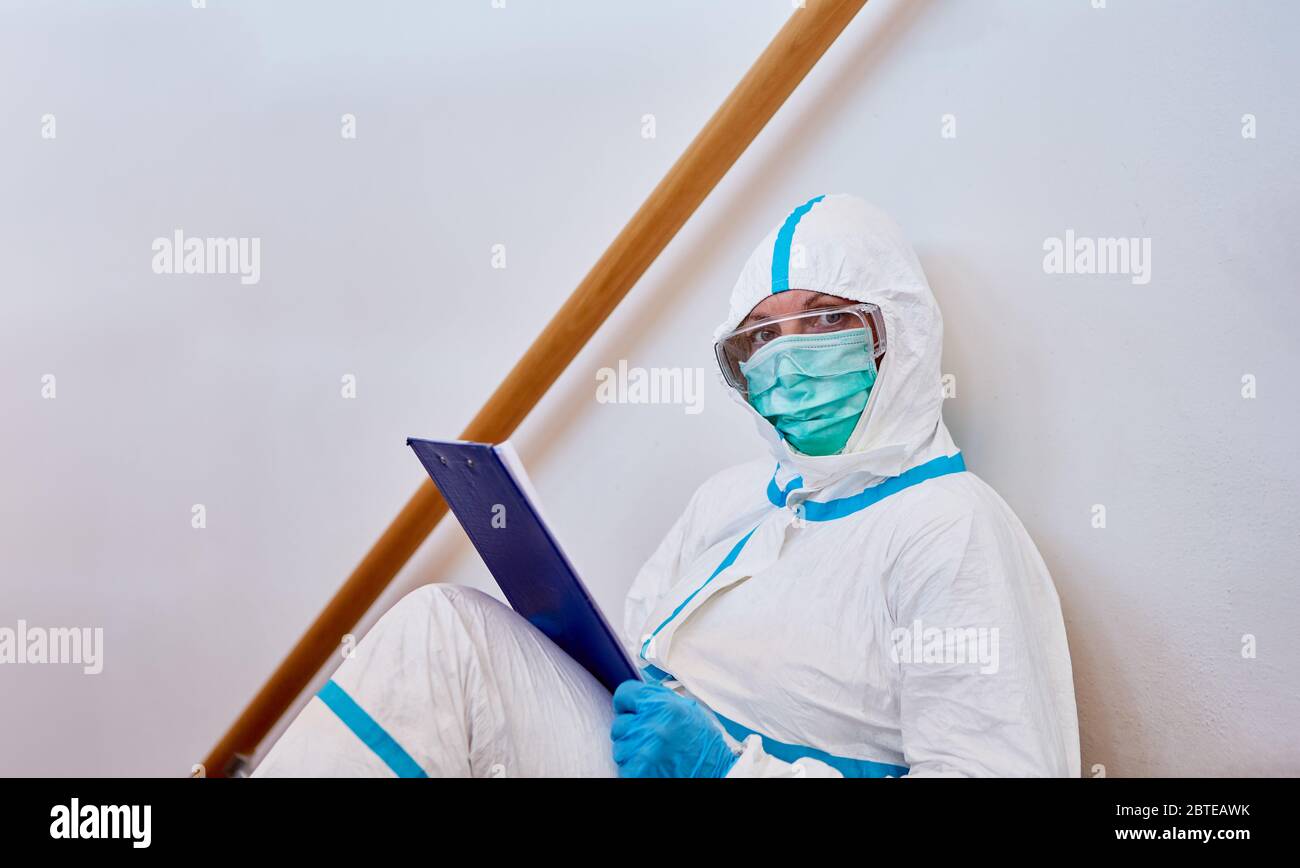 Scout di contenimento con checklist per il monitoraggio dei contatti sulle scale da casa o clinica in pandemia di coronavirus Foto Stock