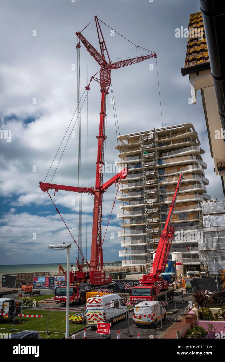 Una gru massiccia che smantellano una gru di grandi dimensioni in un cantiere. Foto Stock