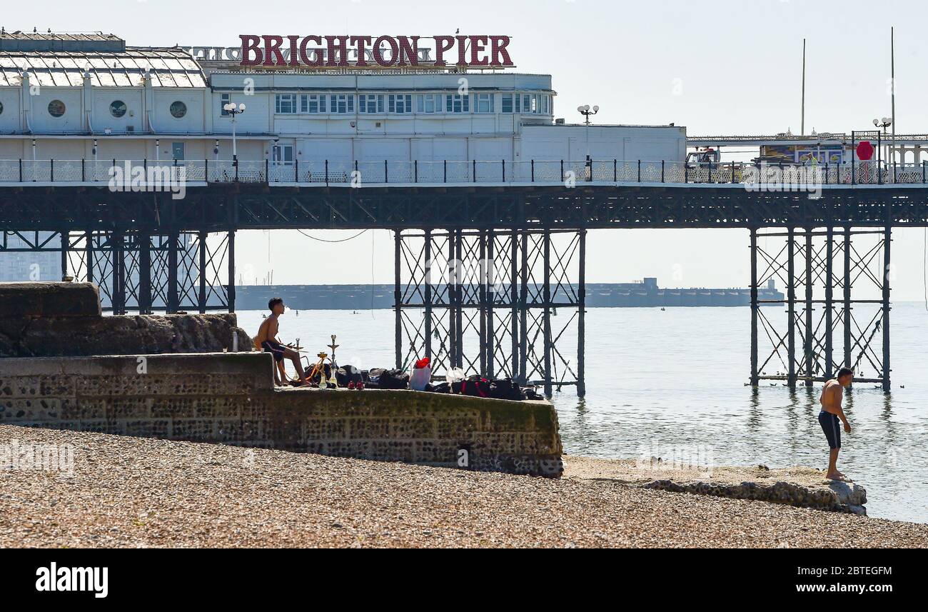 Brighton UK 25 maggio 2020 - i giovani uomini ottengono la festa andando presto sulla spiaggia di Brighton oggi in una giornata calda di sole. Si prevede che le folle si affollino in luoghi di bellezza e spiagge intorno al paese durante le vacanze in banca, poiché si prevede che le temperature raggiungano gli alti 20 anni nel sud-est dell'Inghilterra durante la crisi pandemica di Coronavirus COVID-19 . Credit: Simon Dack / Alamy Live News Foto Stock