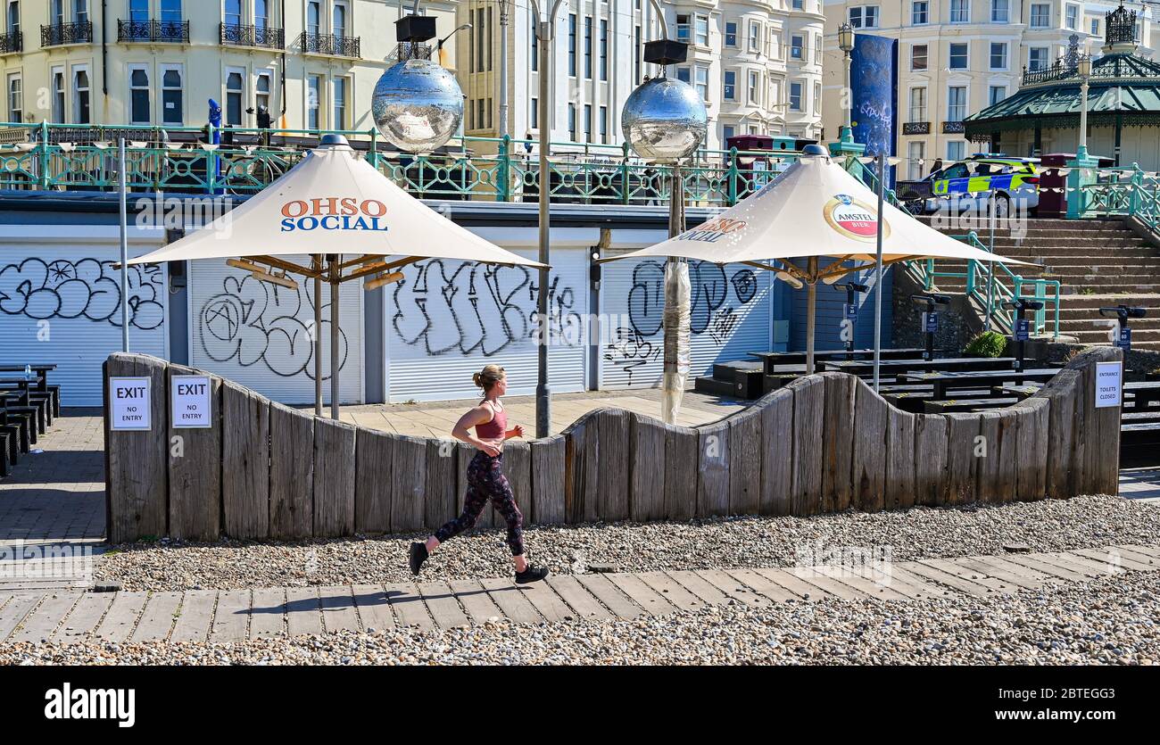 Brighton UK 25 maggio 2020 - UN corridore gode il sole caldo bello sulla spiaggia di Brighton presto oggi come la folla si aspetta che si radunino ai punti di bellezza e alle spiagge intorno al paese durante le feste di banca come le temperature sono previste per raggiungere gli alti 20 nel sud-est dell'Inghilterra Durante la crisi pandemica del Coronavirus COVID-19 . Credit: Simon Dack / Alamy Live News Foto Stock