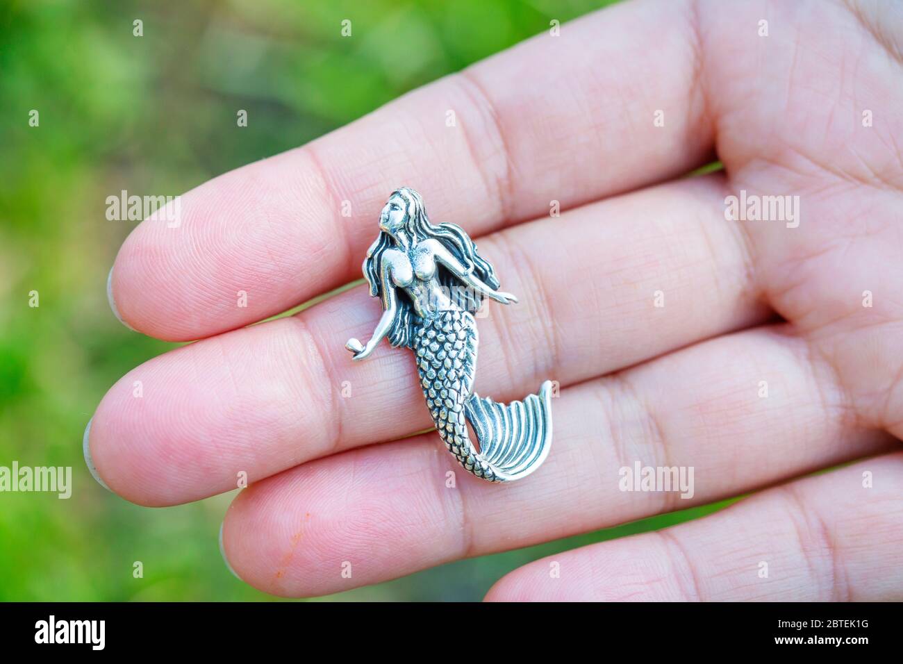 Pendente in argento sterling a forma di sirena sulla mano femminile Foto Stock
