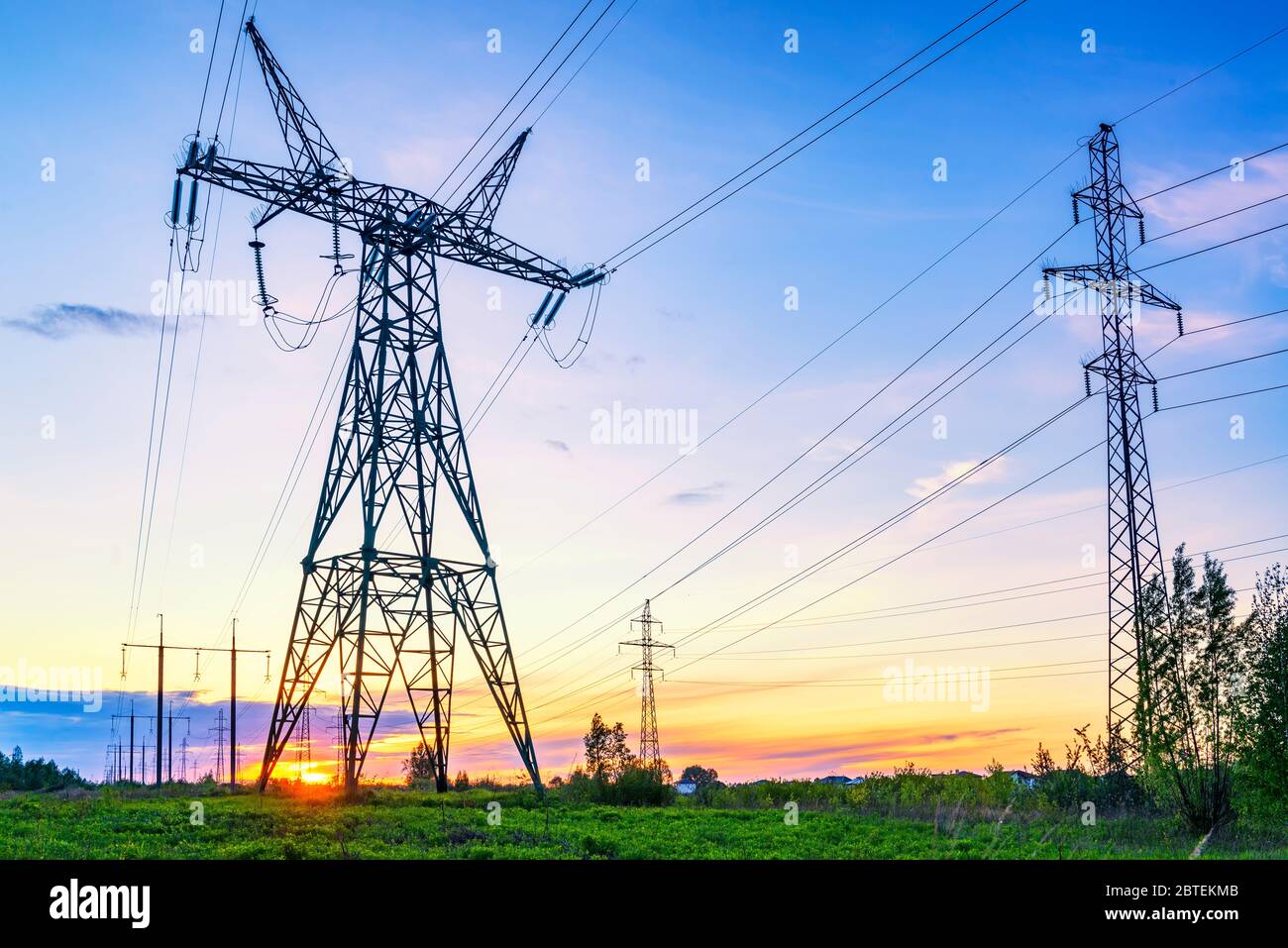 Paesaggio industriale con linee elettriche ad alta tensione al tramonto Foto Stock