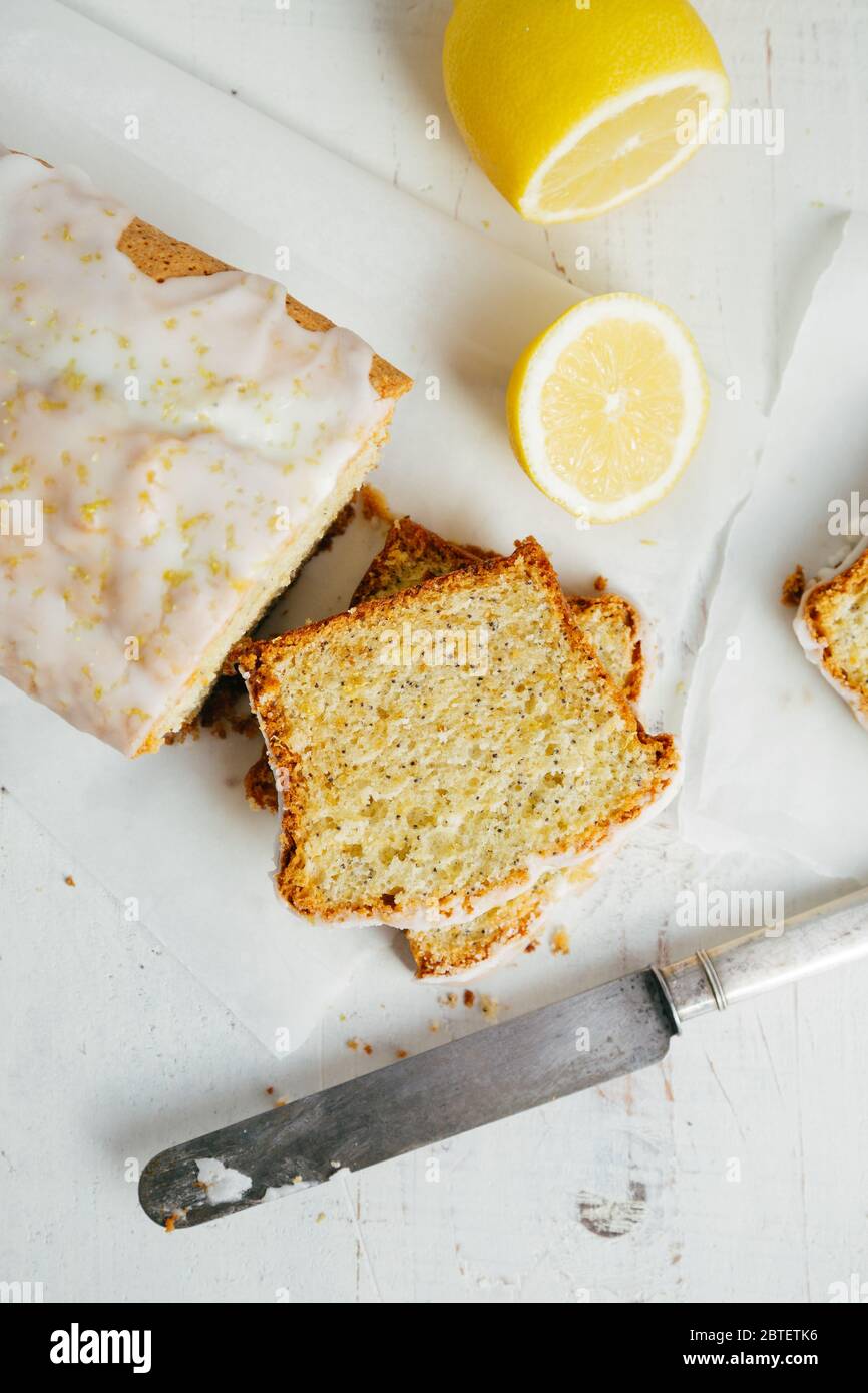 Pagnotta di torta di libbra di limone smaltata con seme di papavero e scorza di limone su un tavolo di legno rustico bianco. Vista dall'alto Foto Stock
