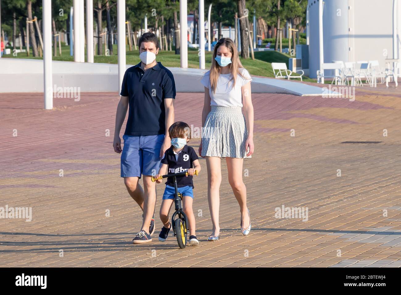 Huelva, Spagna - 23 maggio 2020: Giovane coppia con il figlio che cammina sulla passeggiata di Huelva al tramonto, indossando maschere protettive o mediche durante la a Foto Stock