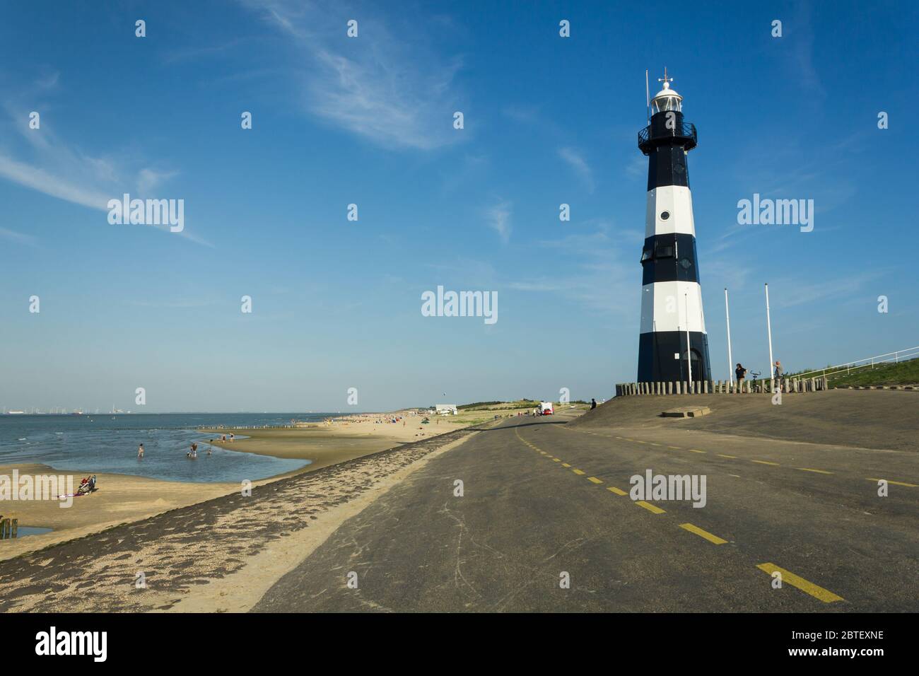 Il faro 'Nieuwe Sluis' a Breskens di giorno durante l'estate con diversi turisti sulla spiaggia Foto Stock