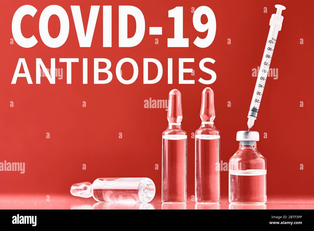 Concetto di anticorpo di coronavirus STI-1499. Siringa medica e farmaco su sfondo rosso con iscrizione COVID-19 anticorpi Foto Stock