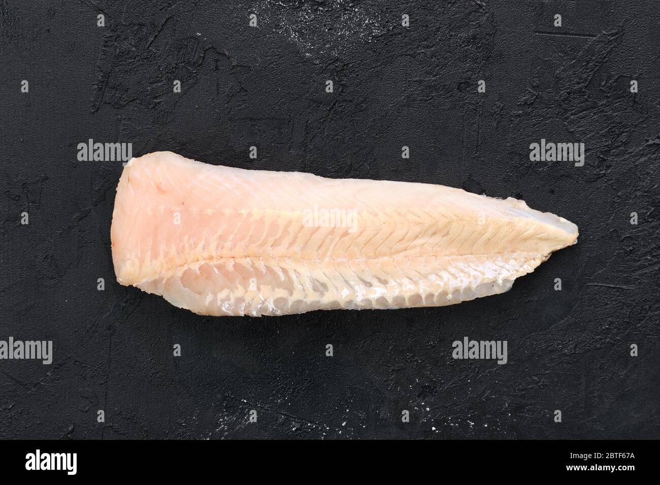 Filetto di nasello crudo poco profondo su fondo nero Foto Stock