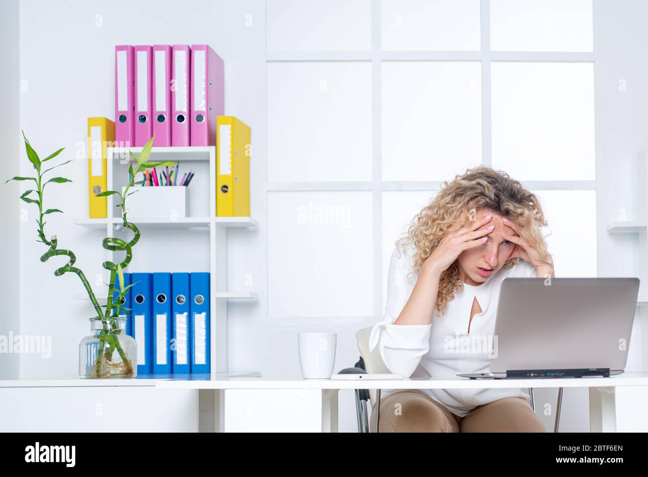 Donna d'affari stanca e sonnolenta alla scrivania con un computer portatile. Stanco lavoratore d'ufficio Foto Stock