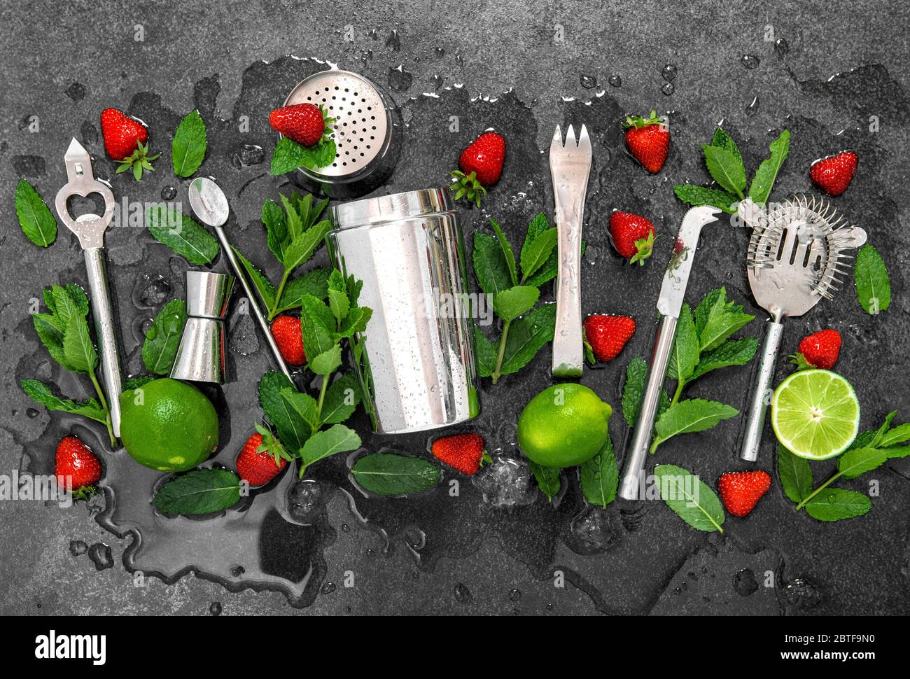 Accessori da bar e ingredienti per cocktail di fragole, lime, menta, ghiaccio Foto Stock