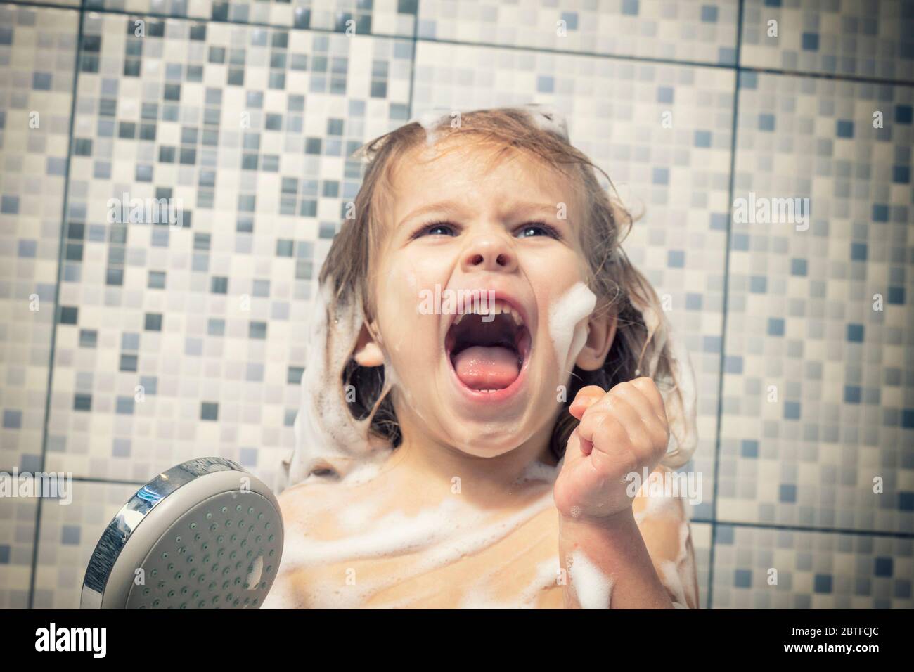 un bambino di 4 anni è coperto di schiuma in una vasca da bagno in mano,