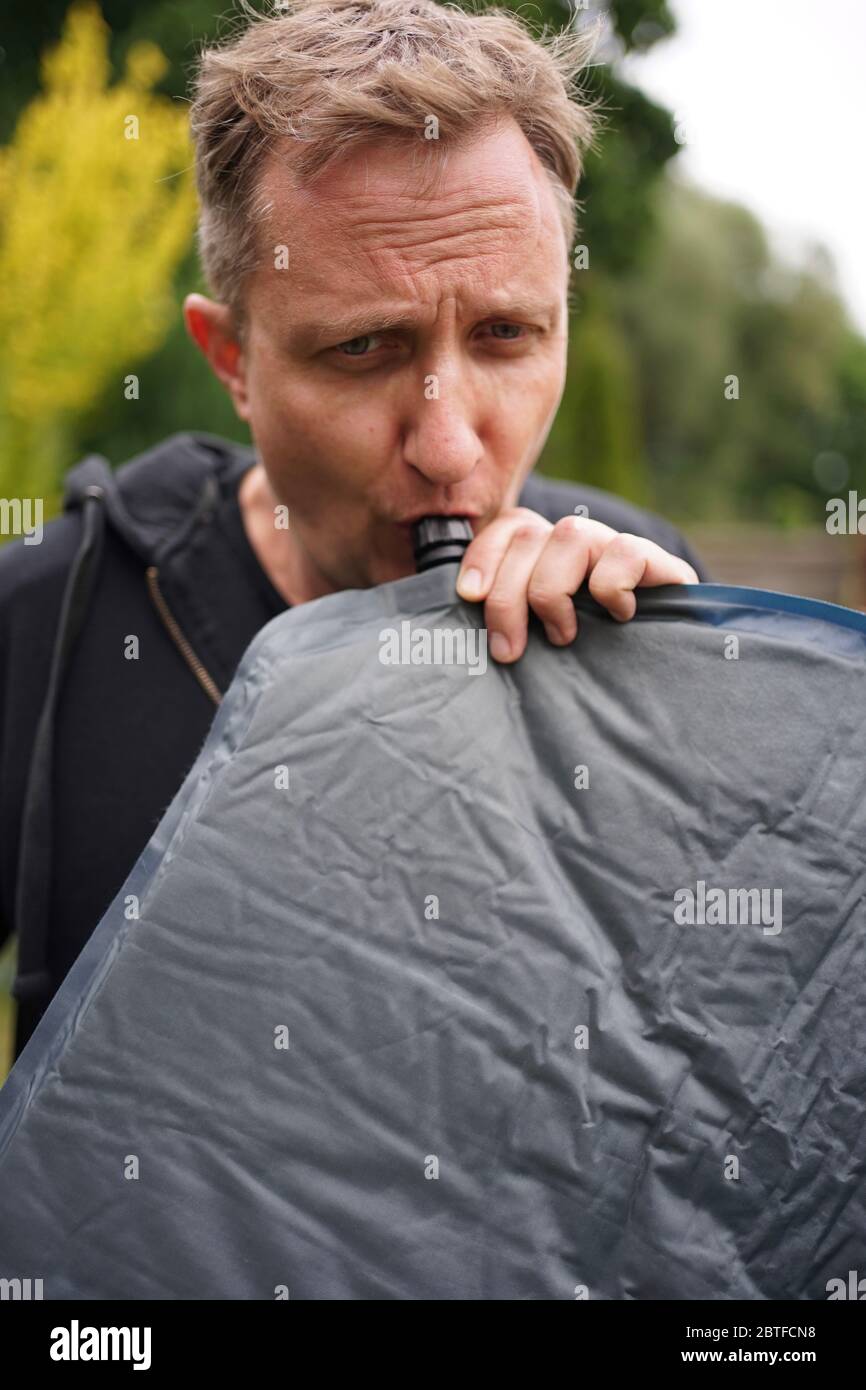 Primo piano di uomo che soffia su un cuscino gonfiabile auto per il  campeggio Foto stock - Alamy
