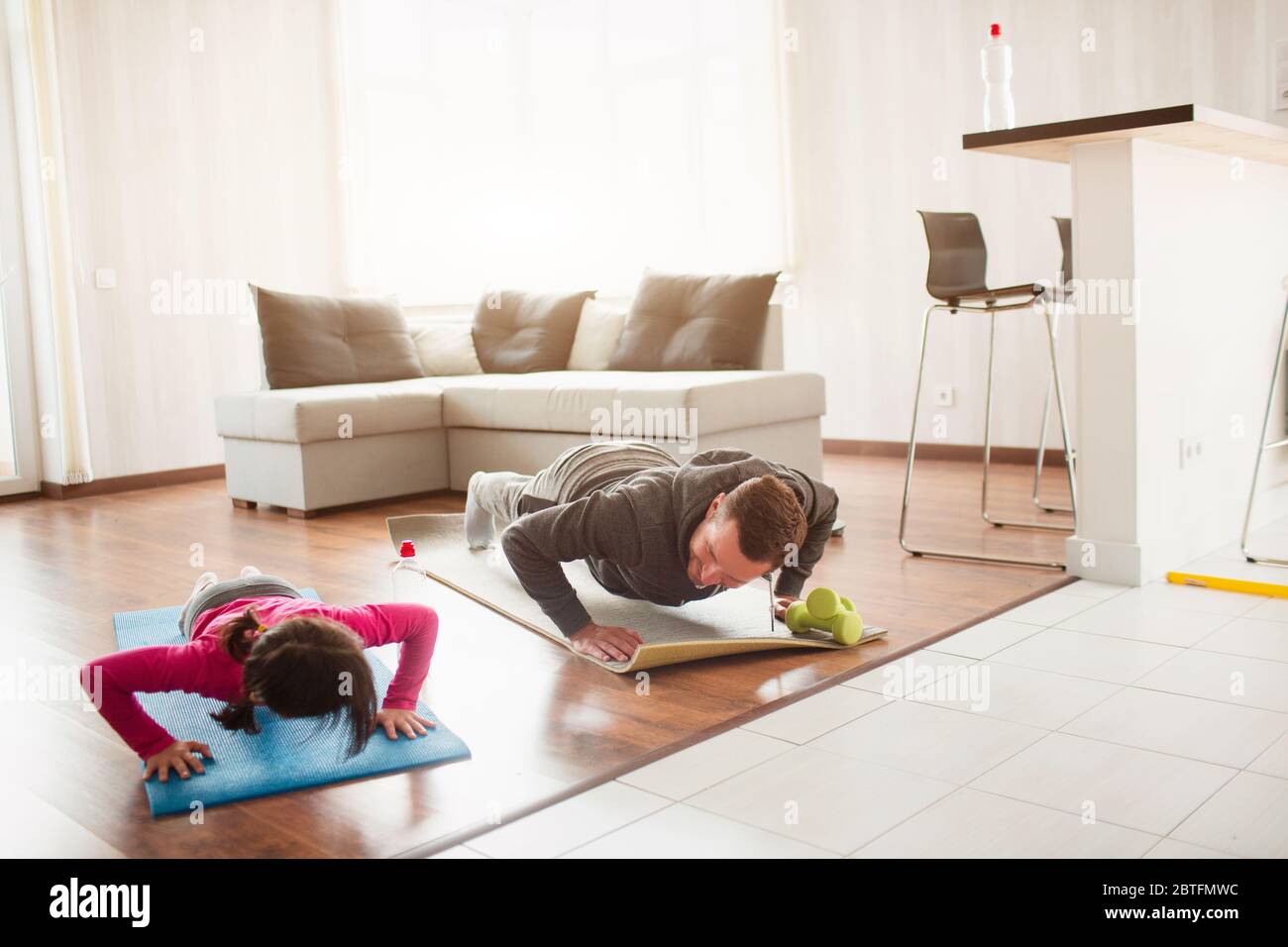 padre e figlia si stanno allenando a casa. Allenati nell'appartamento. Sport a casa. Spingono insieme sul pavimento su tappetini yoga. Foto Stock