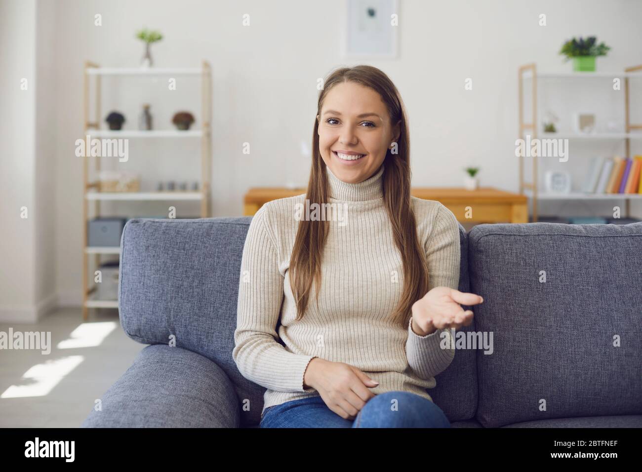 La ragazza felice sorride alla macchina fotografica fa un'intervista in linea utilizzando una conferenza con videochiamata in chat, lezione del webinar in una soggiorno Foto Stock