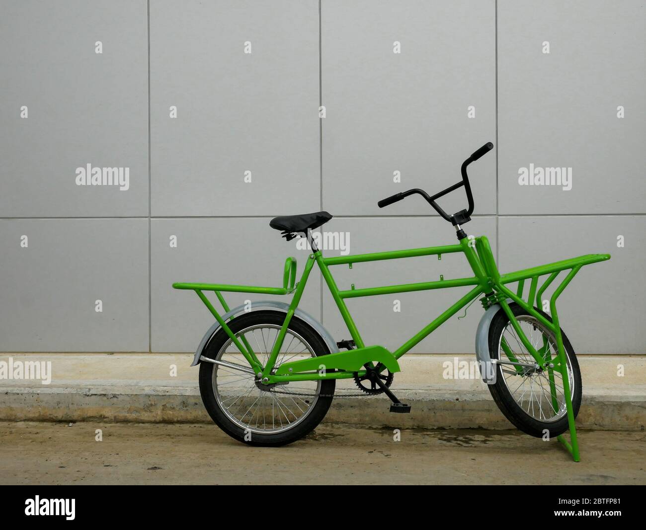 Bicicletta da carico verde per il trasporto dei lavoratori di fronte a un edificio industriale nessuno spazio di copia Foto Stock