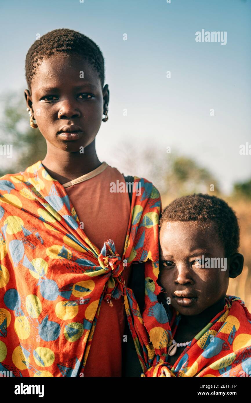 TRIBÙ BOYA, SUD SUDAN - 10 MARZO 2020: Bambini di Boya Tribe indossano pezzi di tessuto brillante e guardando la macchina fotografica mentre si è in piedi su sfocato Foto Stock