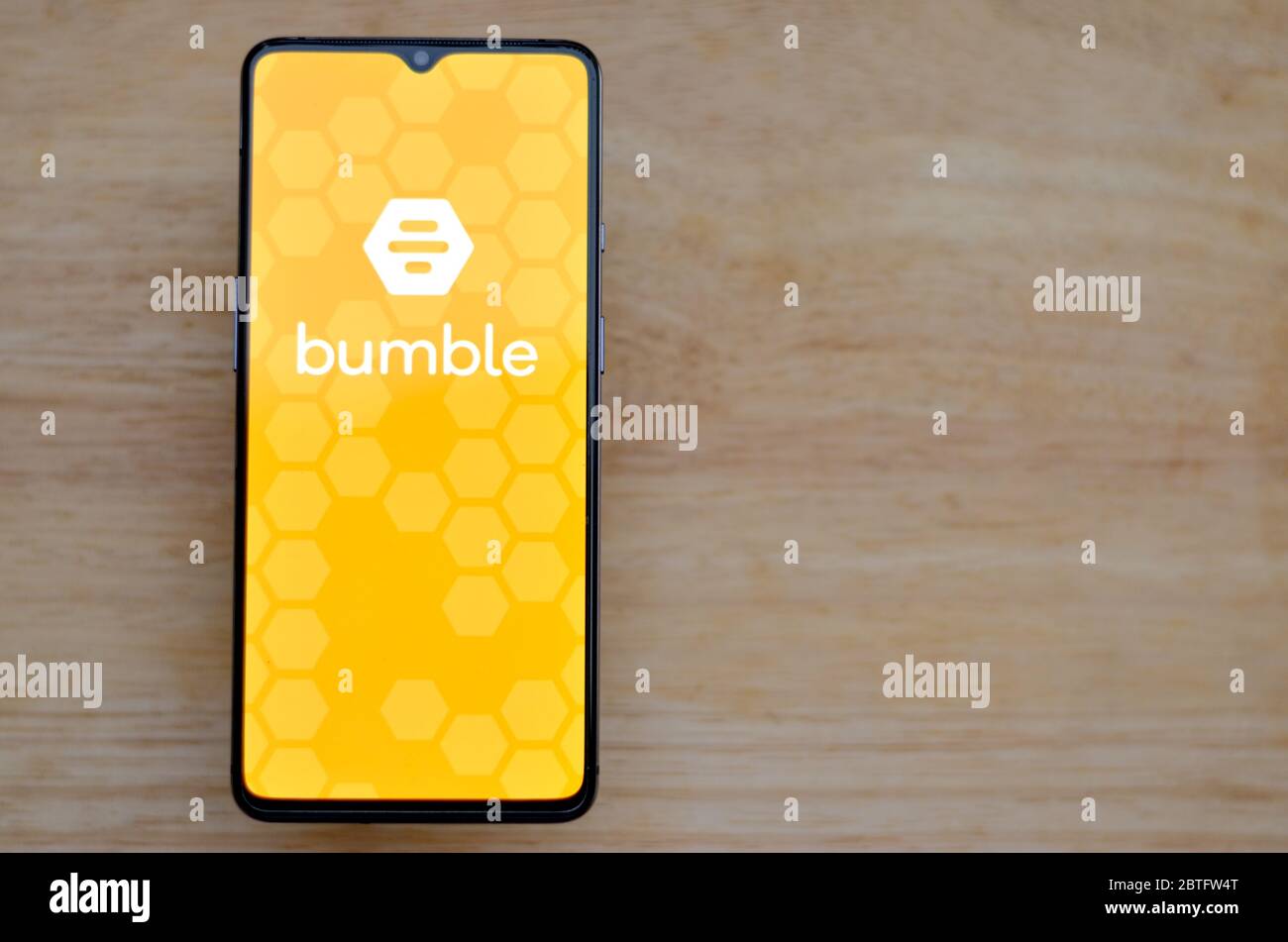 Londra, Inghilterra, Regno Unito, 2020. Disposizione piatta con sfondo in legno e logo dell'app Bumble sullo schermo dello smartphone. Bumble è un calzino online Foto Stock