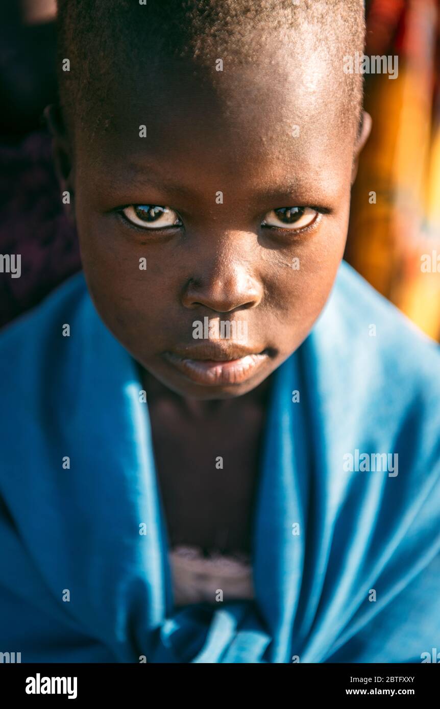 TRIBÙ BOYA, SUD SUDAN - 10 MARZO 2020: Bambino avvolto in tessuto blu guardando la macchina fotografica mentre vive nel villaggio di Boya Tribe, nel Sud Sudan, Africa Foto Stock