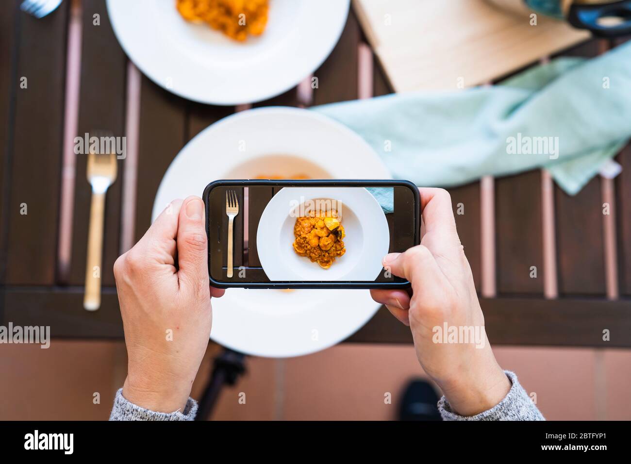 Donna che scatta una foto con il suo smartphone di un delizioso piatto di riso tipico. Foto Stock